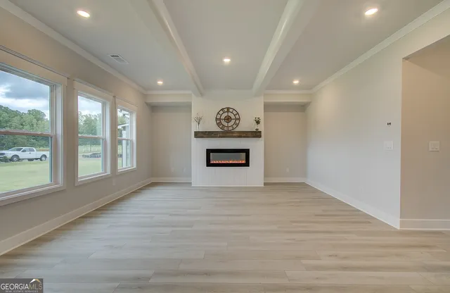 a view of an empty room with a window and a kitchen