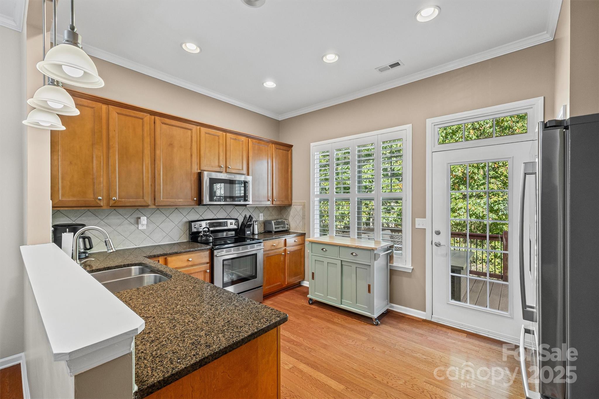 2090 Calloway Pines Drive Tega Cay, SC 29708 - Photo 7 of 38 a kitchen with granite countertop a stove top oven a sink dishwasher a dining table and chairs with wooden floor