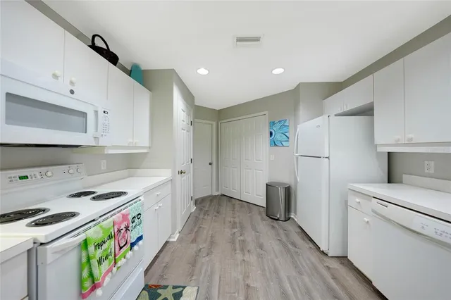 a kitchen that has a lot of white cabinets and stainless steel appliances