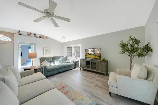 a living room with furniture a ceiling fan and a flat screen tv