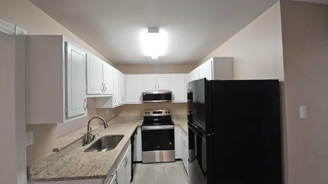 a kitchen with stainless steel appliances granite countertop a stove a refrigerator and a sink