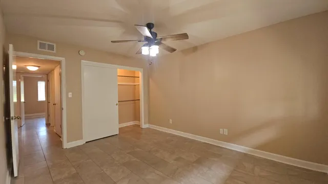 an empty room with closet and a chandelier fan