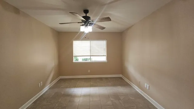 an empty room with windows and fan