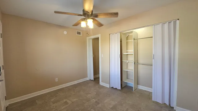 an empty room with closet and a chandelier fan