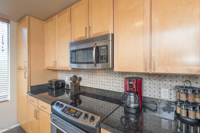 a kitchen with stainless steel appliances granite countertop a stove a sink and a microwave