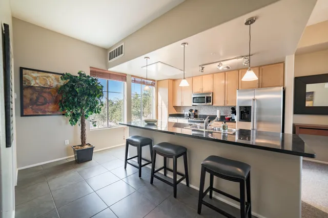 a kitchen with stainless steel appliances a table and chairs in it