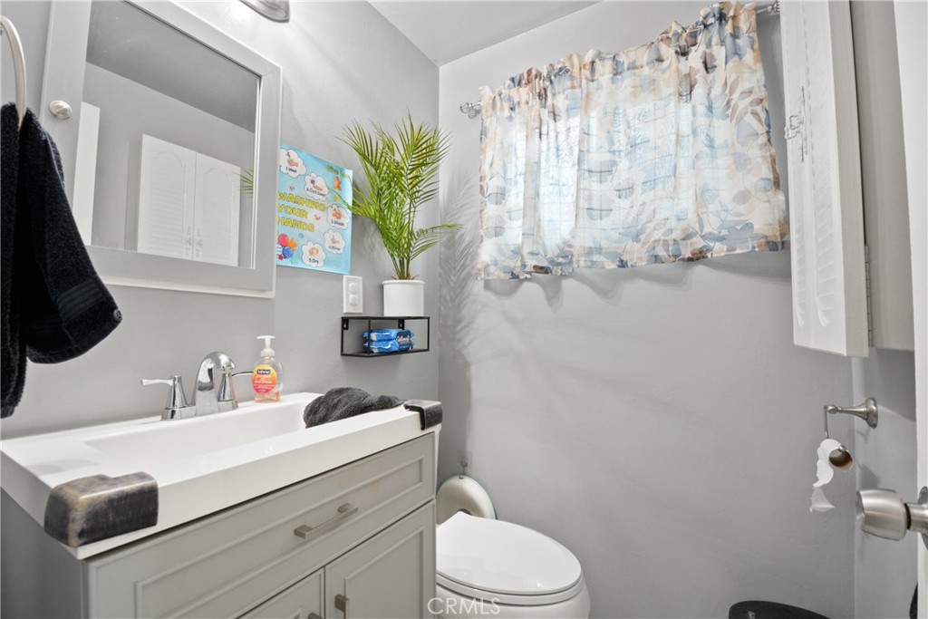 14049 Foster Road La Mirada, CA 90638 - Photo 7 of 16 a bathroom with a sink a toilet and a mirror