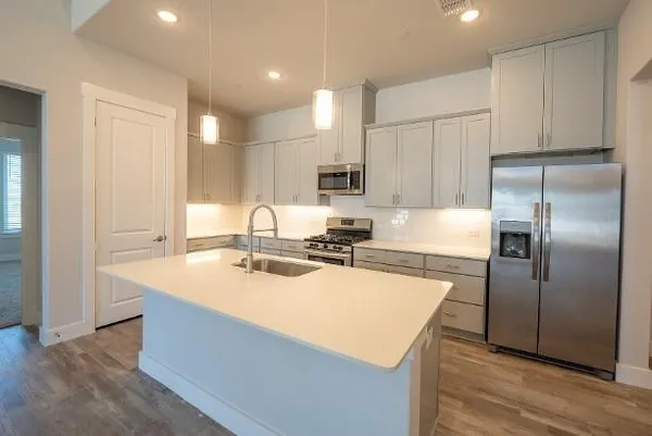 a kitchen with stainless steel appliances granite countertop a refrigerator sink and white cabinets
