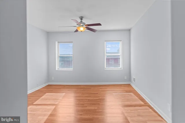 a view of empty room with wooden floor and fan