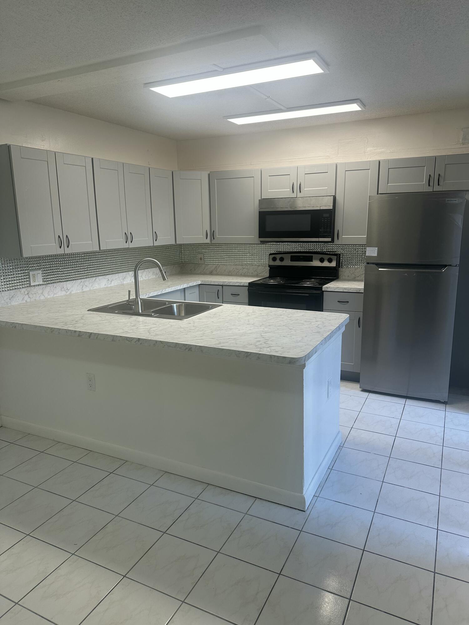 5834 58th Way West Palm Beach, FL 33409 - Photo 3 of 14 a kitchen with kitchen island granite countertop a sink a counter top space and cabinets