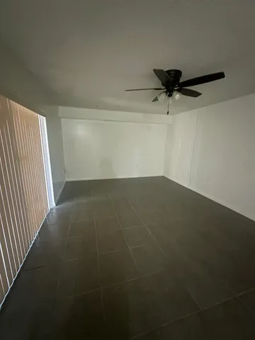 an empty room with a ceiling fan and window