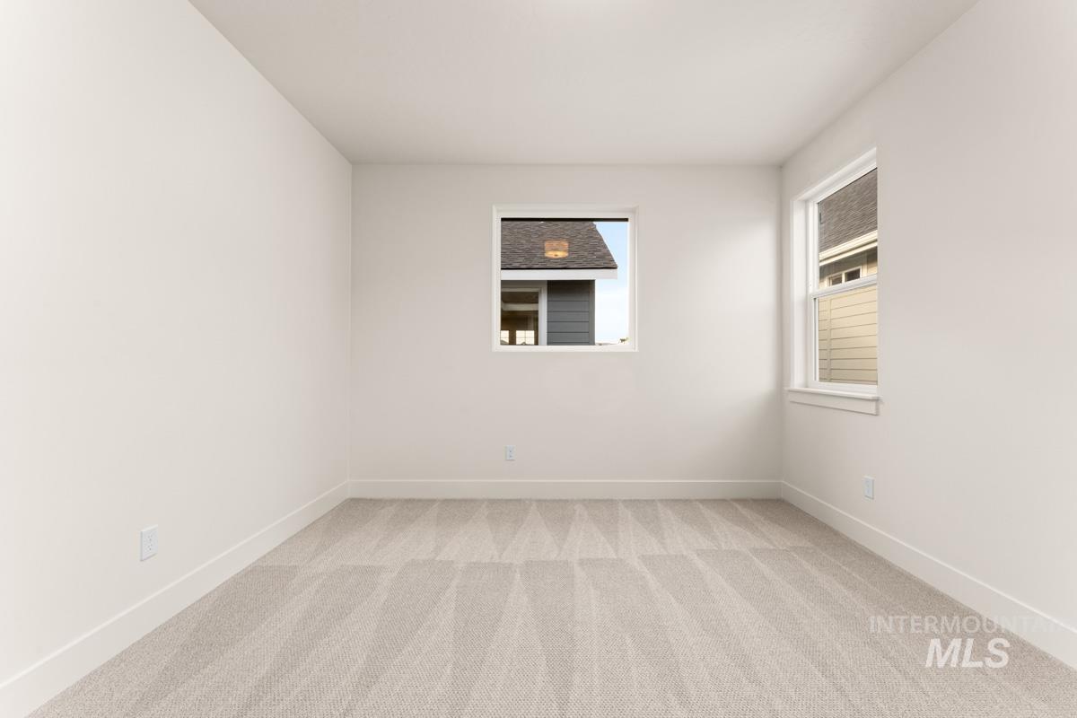 13338 North Spring Creek Way Boise, ID 83714 - Photo 24 of 46 Light-filled room featuring neutral wall paint, two windows with white trim, and patterned carpeting