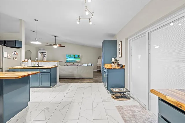 a kitchen with kitchen island granite countertop a refrigerator a sink dishwasher a oven and a dining table with wooden cabinets