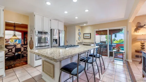 a kitchen with stainless steel appliances granite countertop table chairs and a refrigerator