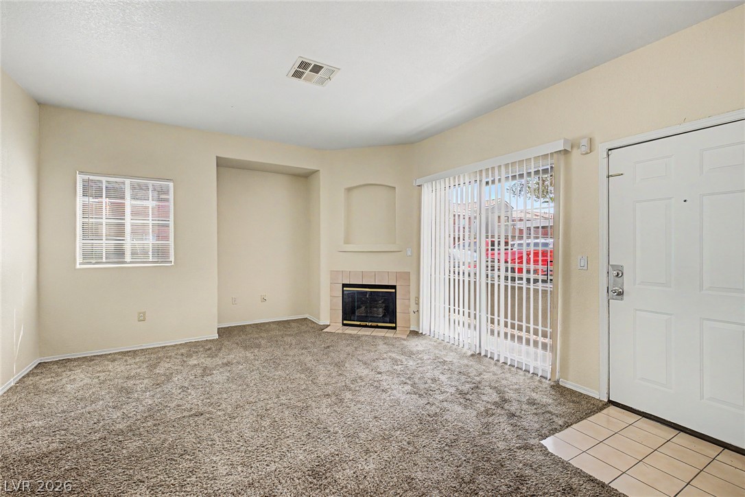 4730 East Craig Road, Unit 1091 Las Vegas, NV 89115 - Photo 4 of 23 Carpeted flooring surrounds a corner fireplace under clean walls and high ceilings.