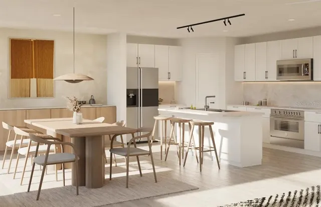 a kitchen with stainless steel appliances kitchen island granite countertop a table chairs and a refrigerator