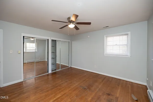 a view of an empty room with a window and wooden floor