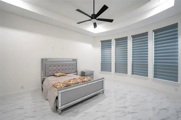 a bed sitting in a bedroom next to a window and a ceiling fan