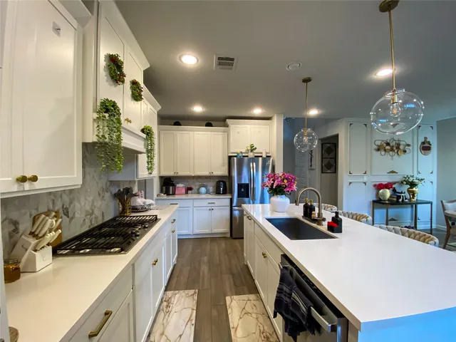 a kitchen that has a lot of white cabinets and stainless steel appliances