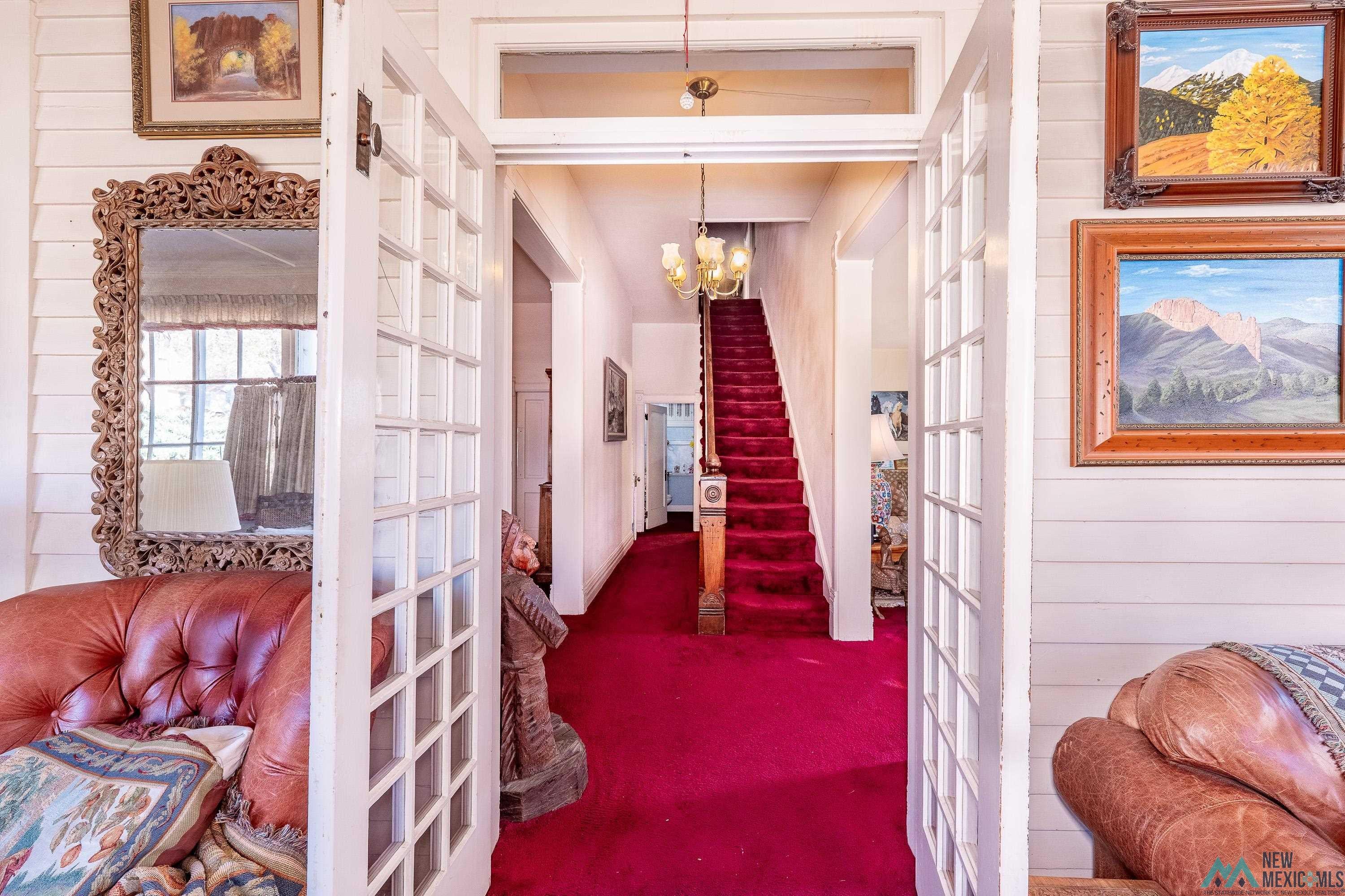 301 South 4th Street Raton, NM 87740 - Photo 13 of 78 Hall featuring french doors, dark colored carpet, a chandelier, and stairway