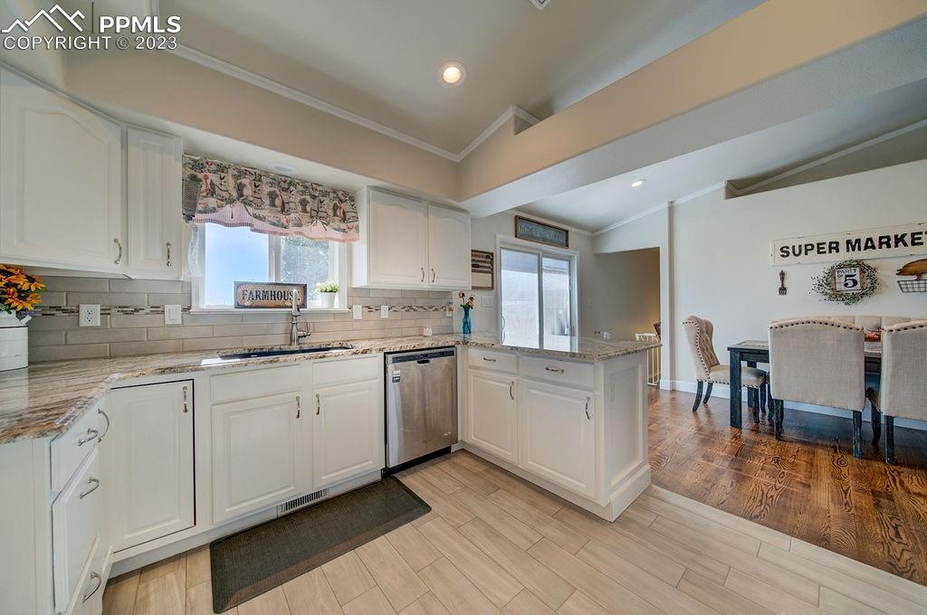 648 South McCulloch Boulevard Pueblo, CO 81007 - Photo 18 of 50 a white kitchen with granite countertop a stove top oven a sink a dining table and chairs