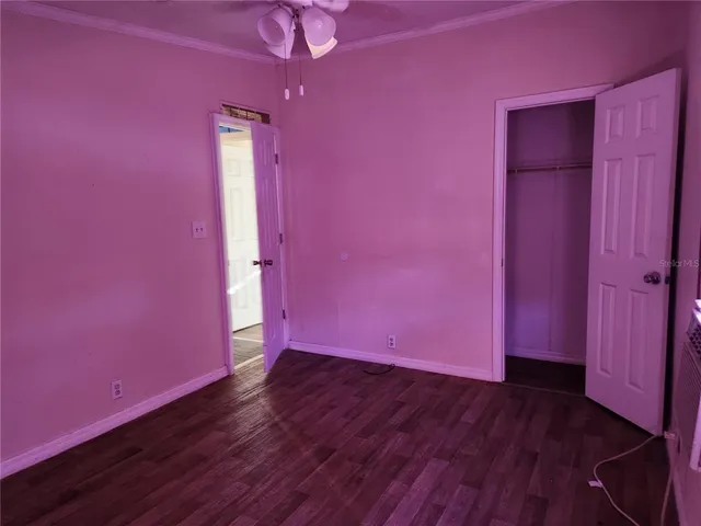 a view of empty room with wooden floor and a window