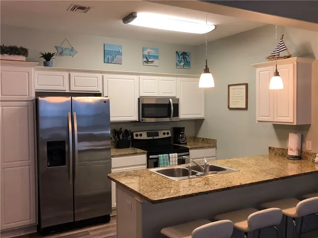 a kitchen with stainless steel appliances granite countertop a sink a microwave a refrigerator and island