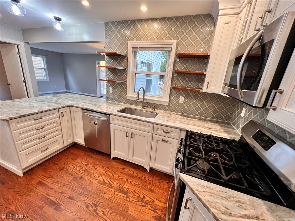1376 Lander Road Cleveland, OH 44124 - Photo 9 of 33 Kitchen with sink, dark hardwood flooring, tasteful backsplash, light stone countertops, and stainless steel appliances