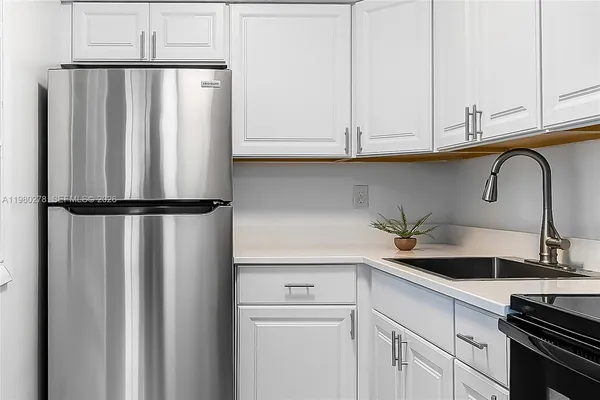 a close view of a sink and dishwasher with white cabinets