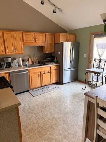 a kitchen with stainless steel appliances granite countertop a refrigerator a stove a sink dishwasher and wooden cabinets with wooden floor