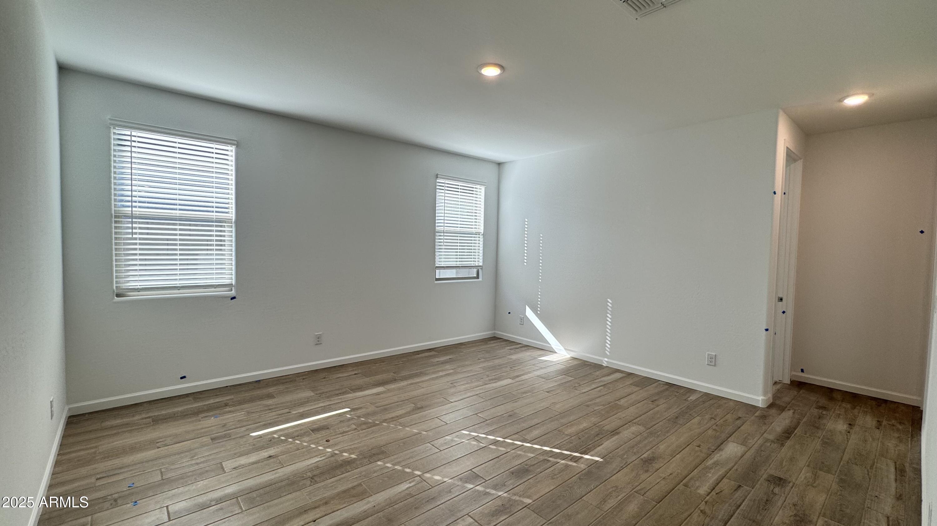 15748 West Camden Avenue Waddell, AZ 85355 - Photo 12 of 36 an empty room with wooden floor and windows
