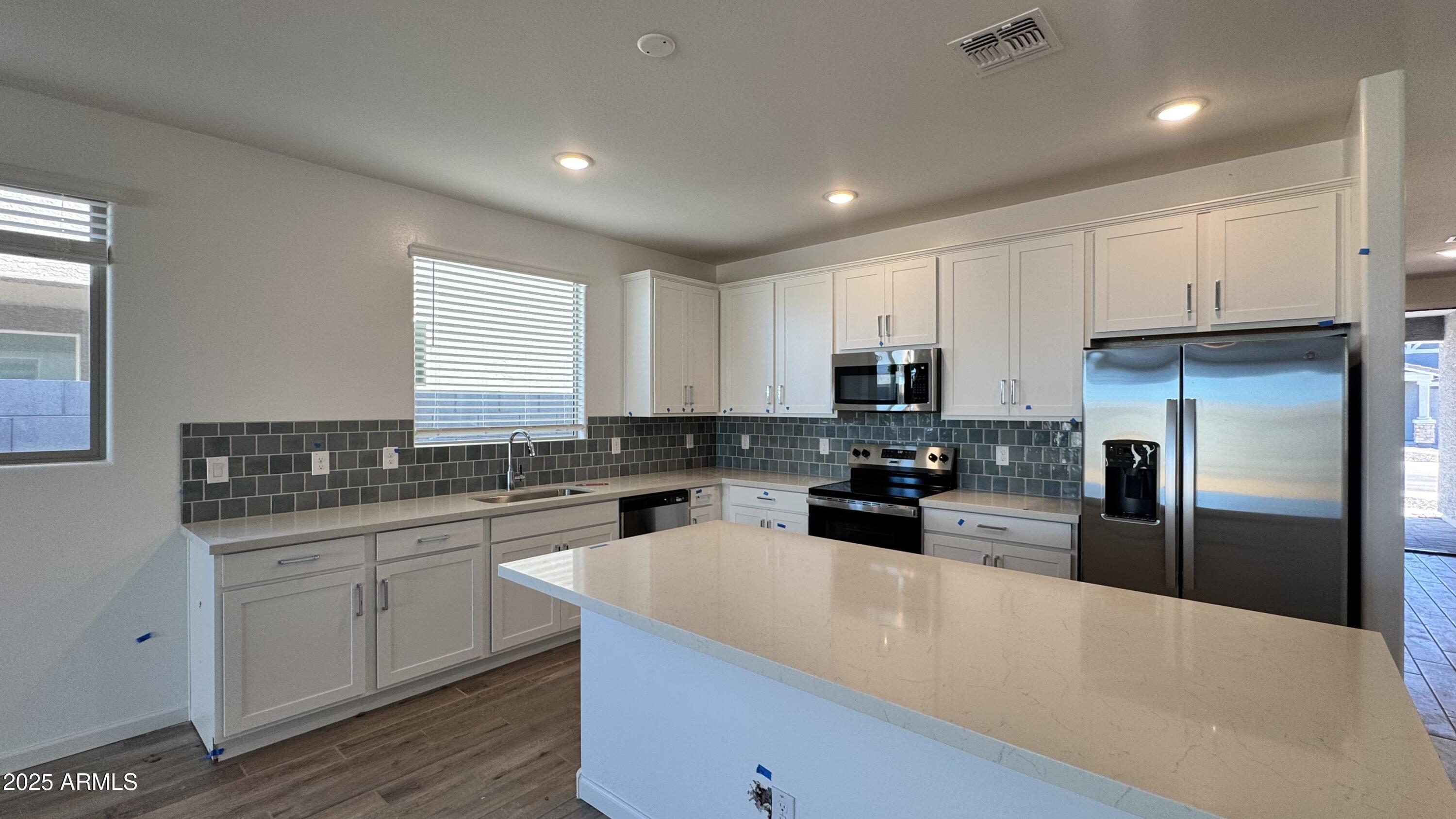 15748 West Camden Avenue Waddell, AZ 85355 - Photo 8 of 36 a kitchen with stainless steel appliances a refrigerator a sink a stove a microwave and cabinets