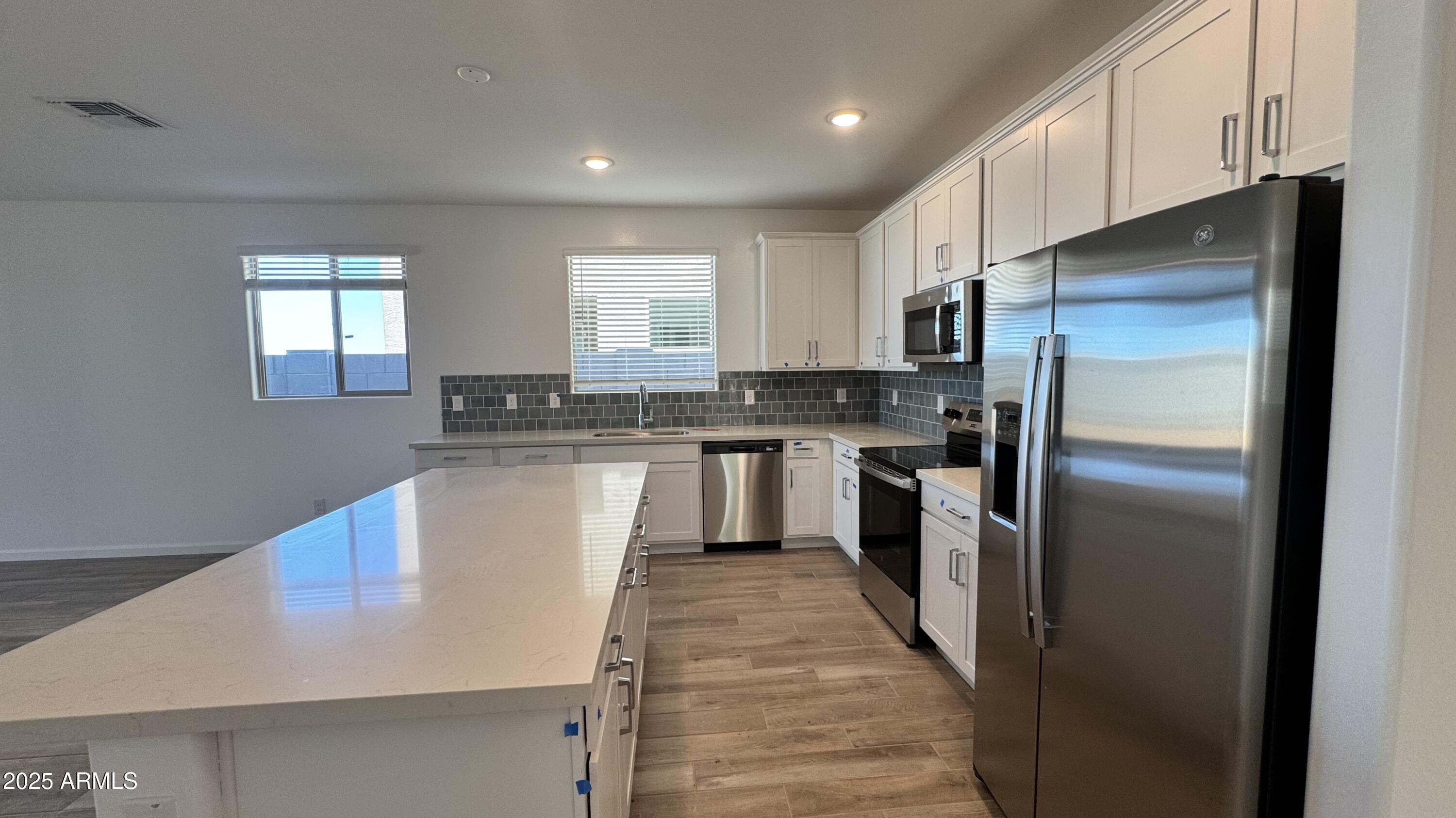 15748 West Camden Avenue Waddell, AZ 85355 - Photo 9 of 36 a kitchen with stainless steel appliances granite countertop a refrigerator a sink a stove a microwave and white cabinets