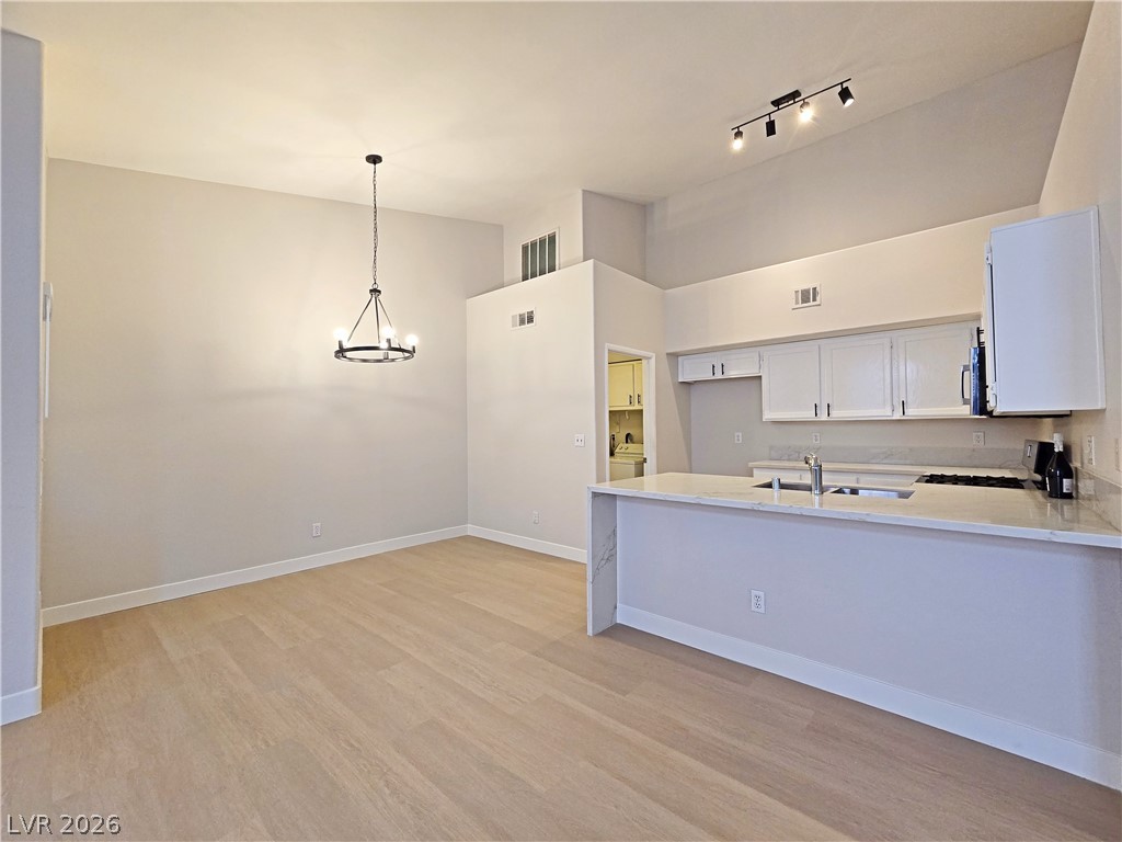 5370 Runningbrook Road Las Vegas, NV 89120 - Photo 12 of 30 An open-concept living space with a vaulted ceiling features a sleek kitchen island and hardwood flooring.