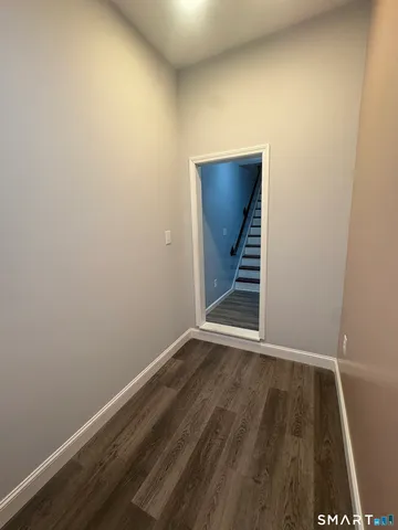 a view of an empty room with wooden floor and stairs