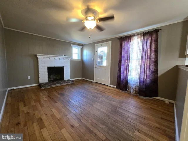 an empty room with windows a fireplace and wooden floor