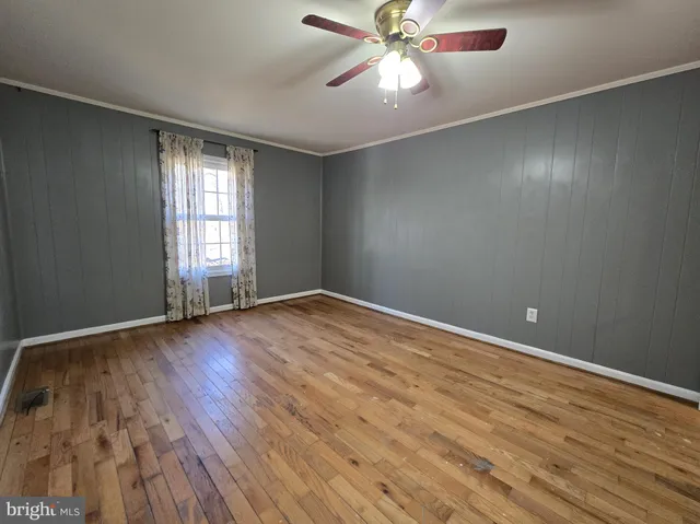 an empty room with wooden floor fan and windows