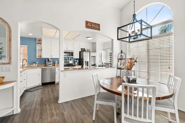 a kitchen with stainless steel appliances kitchen island granite countertop a dining table chairs and a refrigerator