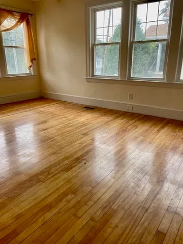 a view of an empty room with wooden floor and a window