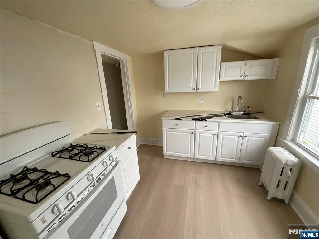 131 Delafield Avenue, Unit 3 Lyndhurst, NJ 07071 - Photo 6 of 15 a kitchen with white cabinets a stove and a sink