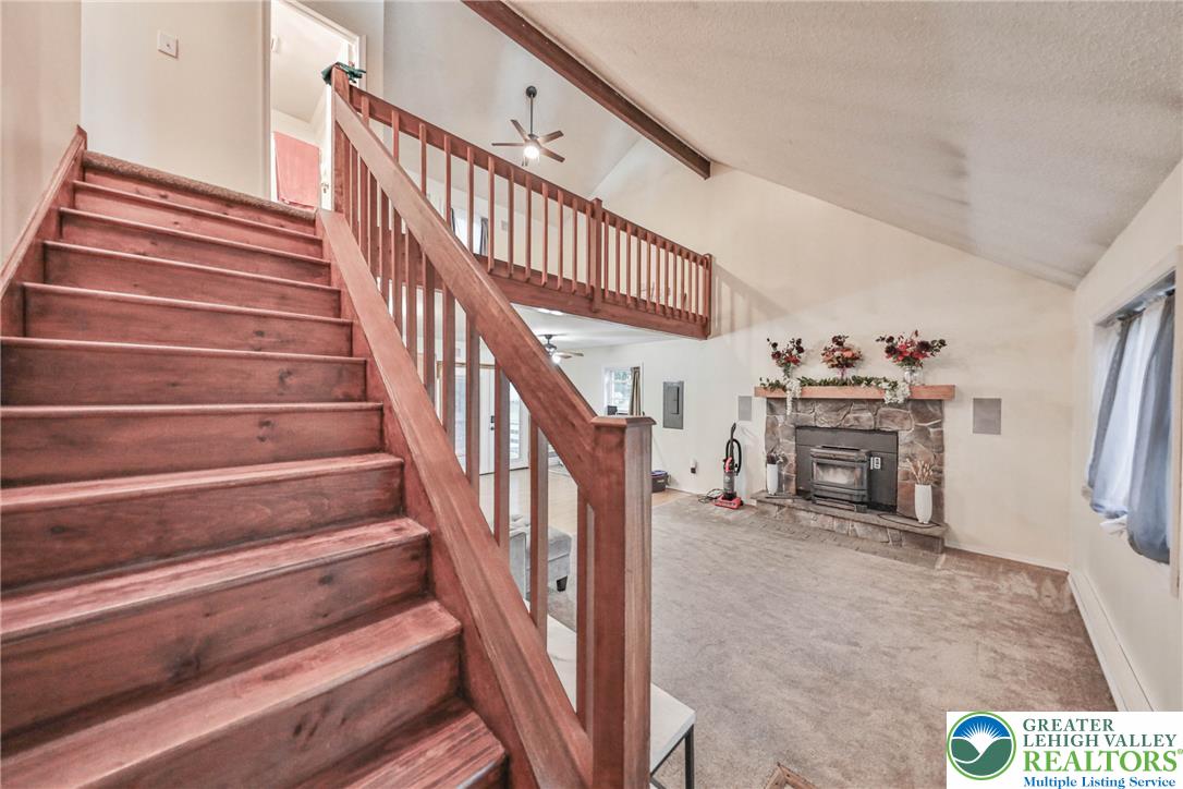 2114 Lakeview Road Bushkill, PA 18324 - Photo 14 of 83 Wooden stairs rise alongside a vaulted living room anchored by a stone fireplace.