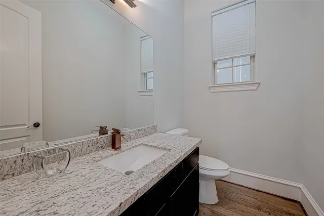 a bathroom with a granite countertop sink and a toilet