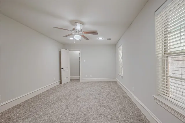 an empty room with a window and a fan