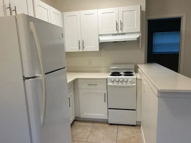 a kitchen with appliances a refrigerator and cabinets