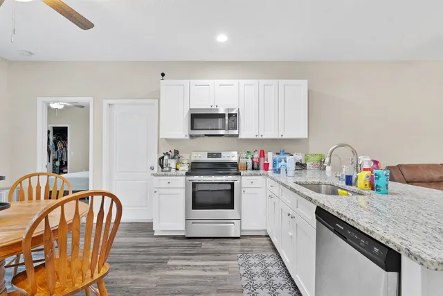 a kitchen with stainless steel appliances granite countertop a stove a sink dishwasher and a refrigerator with wooden cabinets