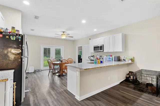 a living room with stainless steel appliances furniture a fireplace a flat screen tv and a window