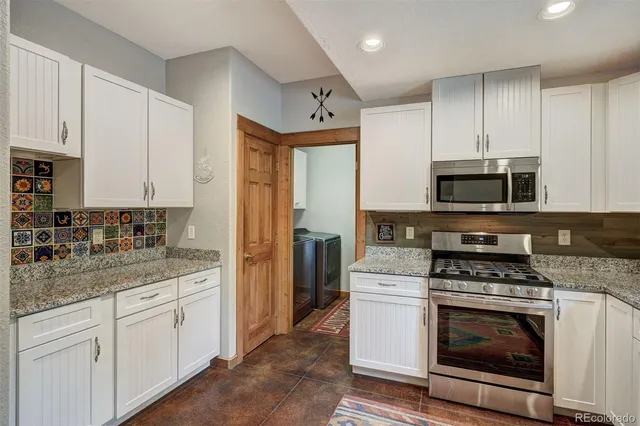 a kitchen with granite countertop white cabinets stainless steel appliances and sink