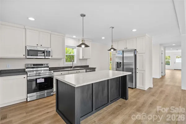 a kitchen with kitchen island a sink stainless steel appliances and wooden floor