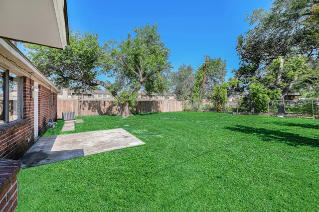 a view of backyard with table and chairs and potted plants and big trees