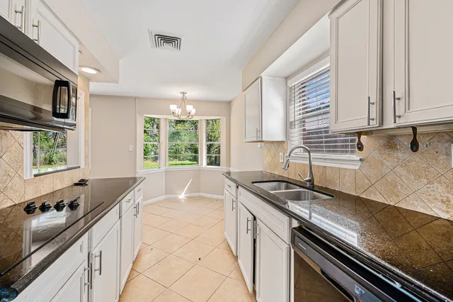 a kitchen with granite countertop stainless steel appliances a sink stove top oven and cabinets
